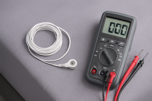 A grounding sheet with a coiled cable and a digital multimeter displaying "0.00" on a gray surface.
