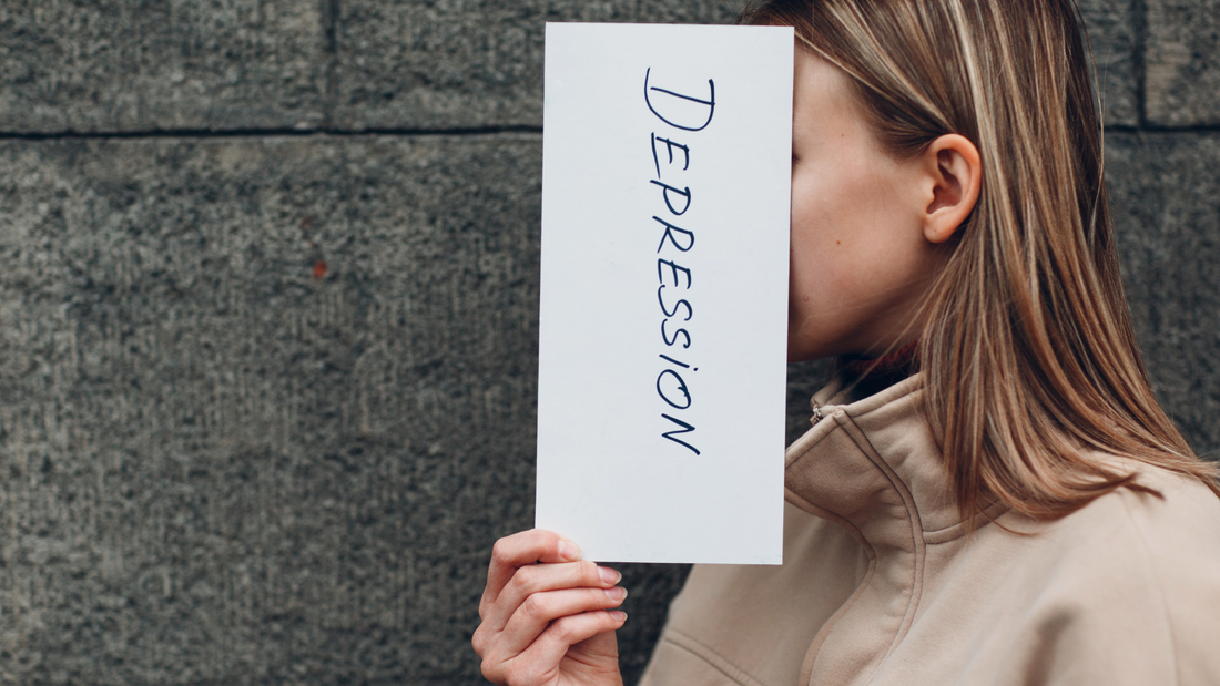a female holding a piece of paper displaying the word "depression."