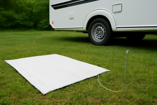 Grounding sheet setup next to an RV with a grounding stake, showing a peaceful outdoor setting