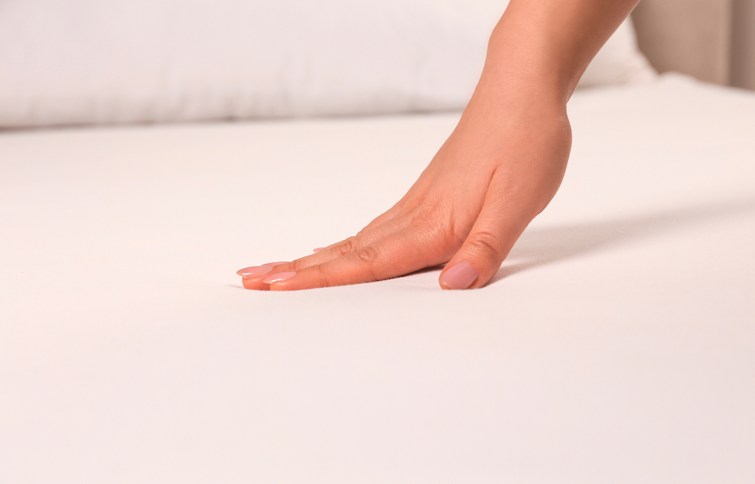 person touching the sheet of the bed