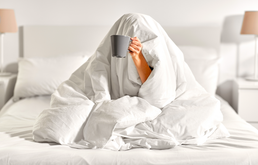 person holding a cup under a blanket
