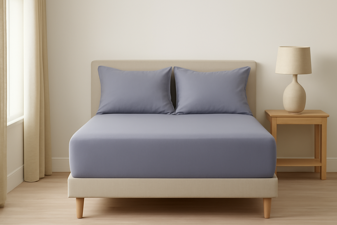 A minimalist bedroom with a bed covered in a fitted gray grounding sheet and matching pillows.