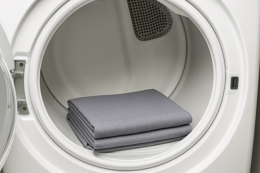 Gray grounding sheet neatly folded and placed inside a white front-loading dryer with the door open.