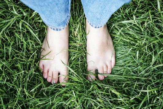 Close-up of bare feet on lush green grass, grounding to Earth