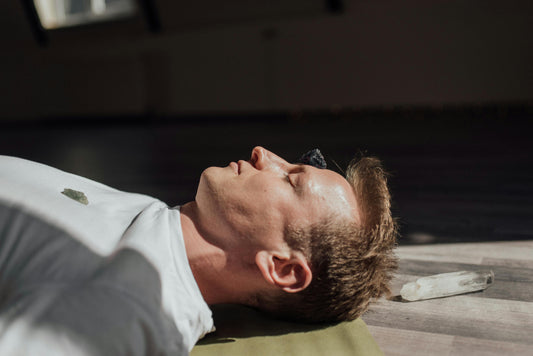 Man lying on a yoga mat with healing crystals on his body