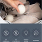 Hand placing wool dryer ball in laundry with benefits list.