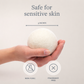 Hand holding a white spherical product with text indicating it's safe for sensitive skin, non-toxic, and fragrance-free.