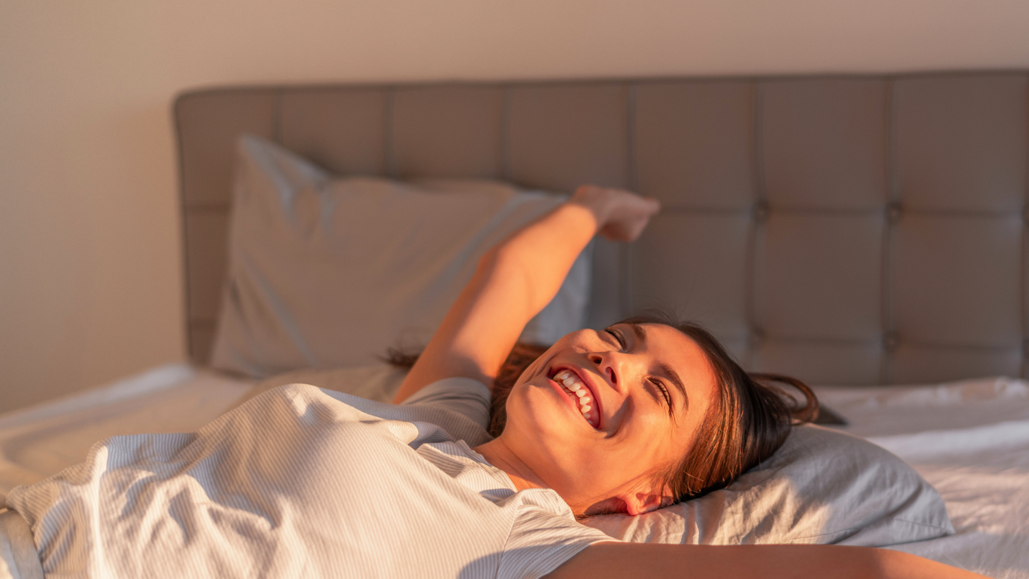 Woman waking up refreshed after sleeping on organic grounding sheets for menopause
